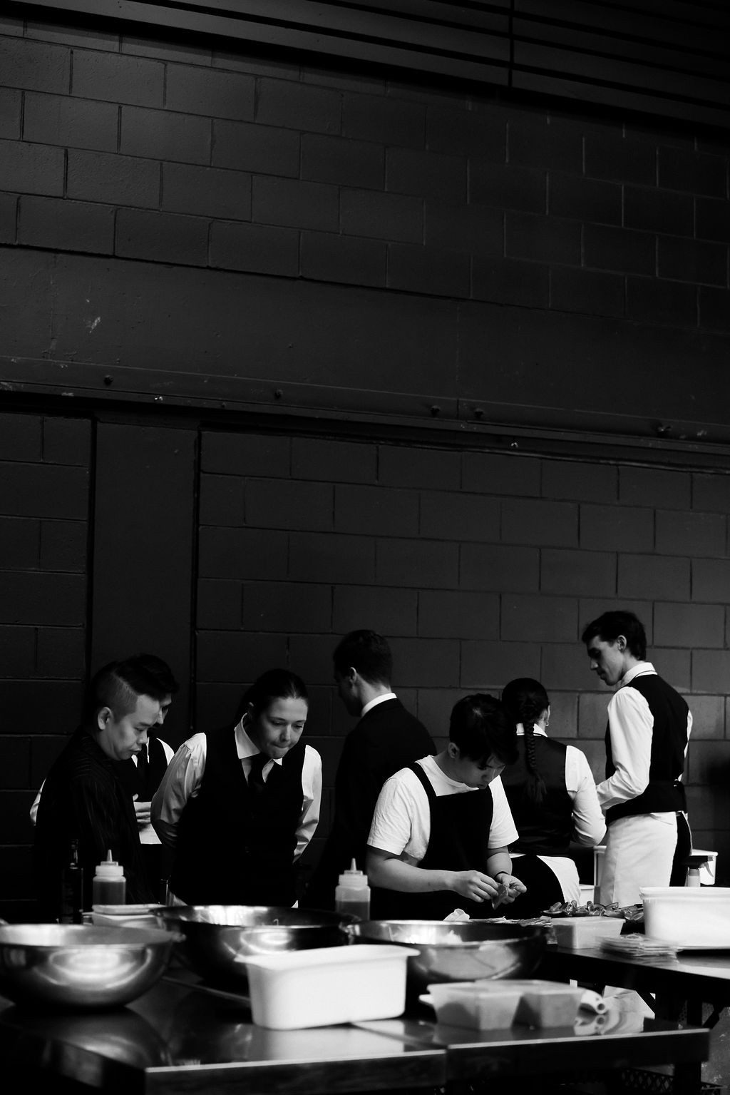 Catering staff in black-and-white preparing service behind the scenes